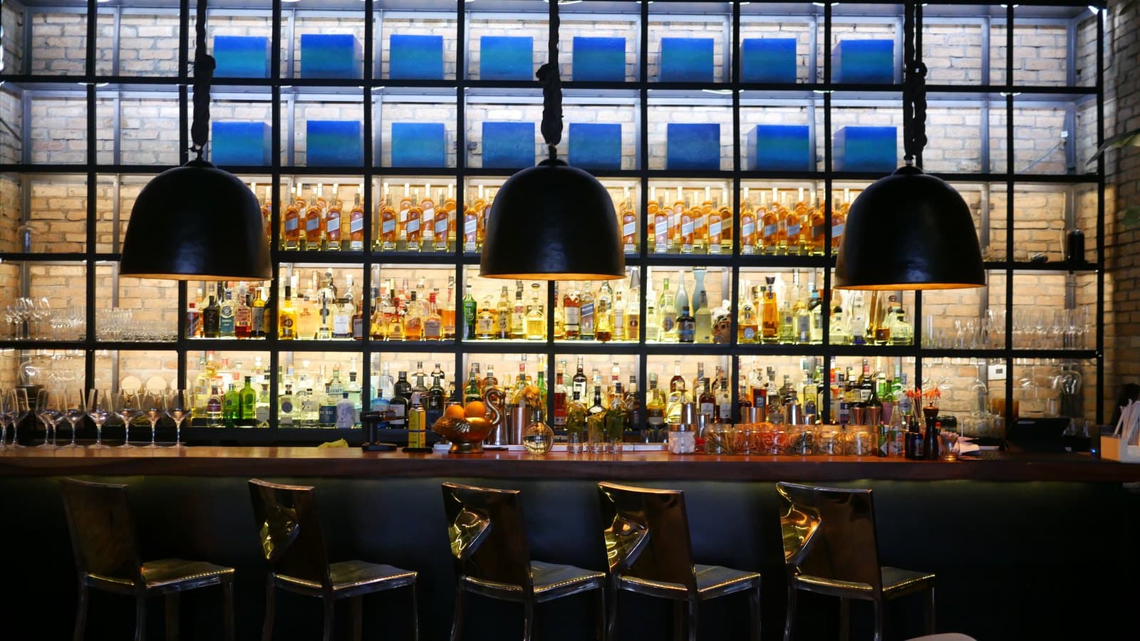 The backlit bottle wall and low pendant lamps over the bar at Azahar, Bella Vista, Panama City