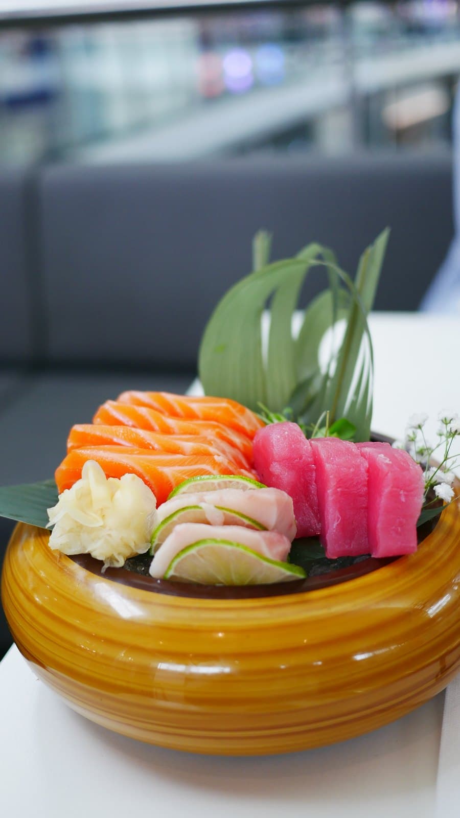 A sashimi plate at Bruttito with salmon, tuna and whitefish on an orange dish