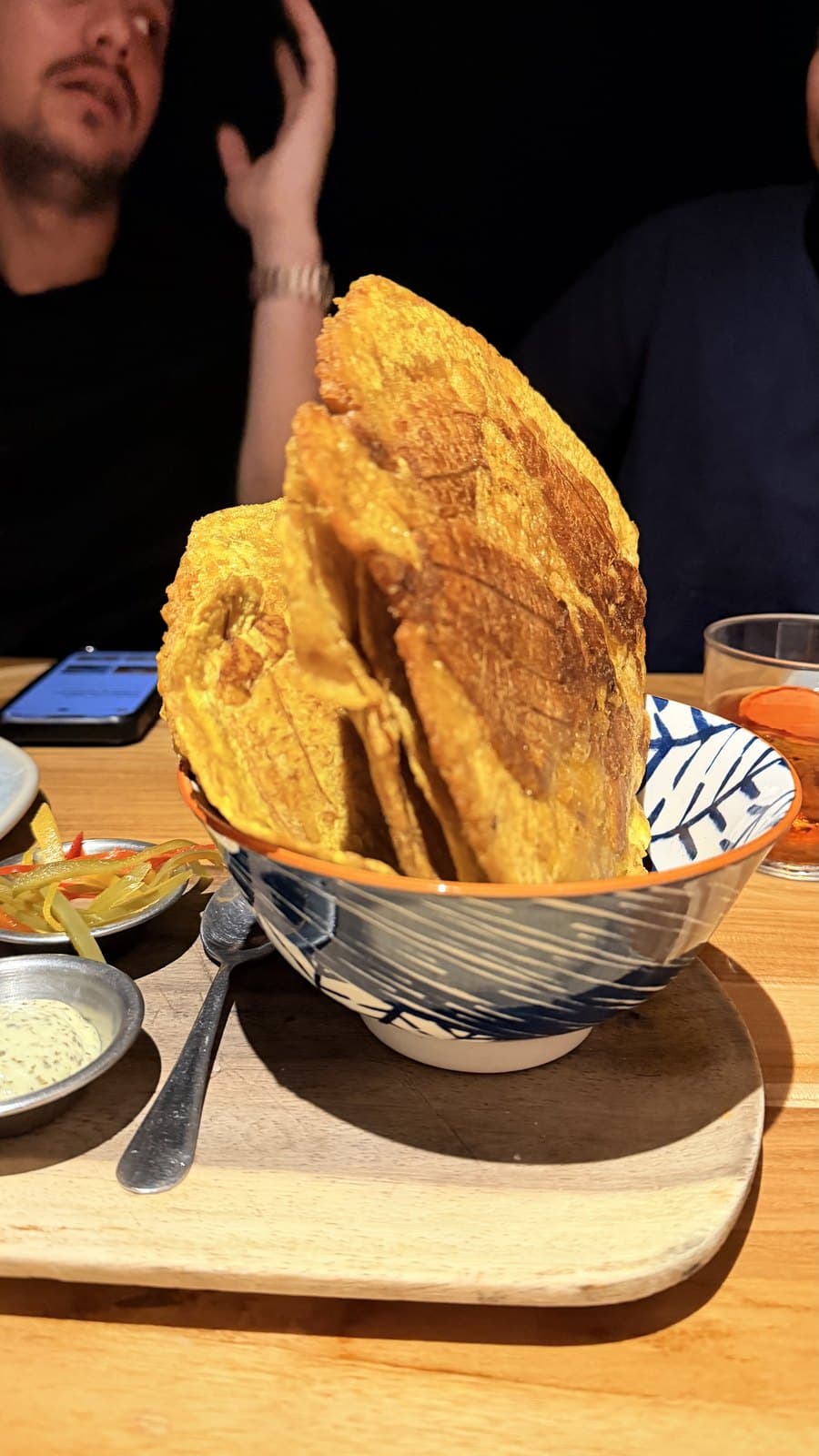 Patacones at Cantina del Tigre: wide, thin slices of fried plantain standing in a patterned bowl, with pickled peppers and a creamy herb dip on the side