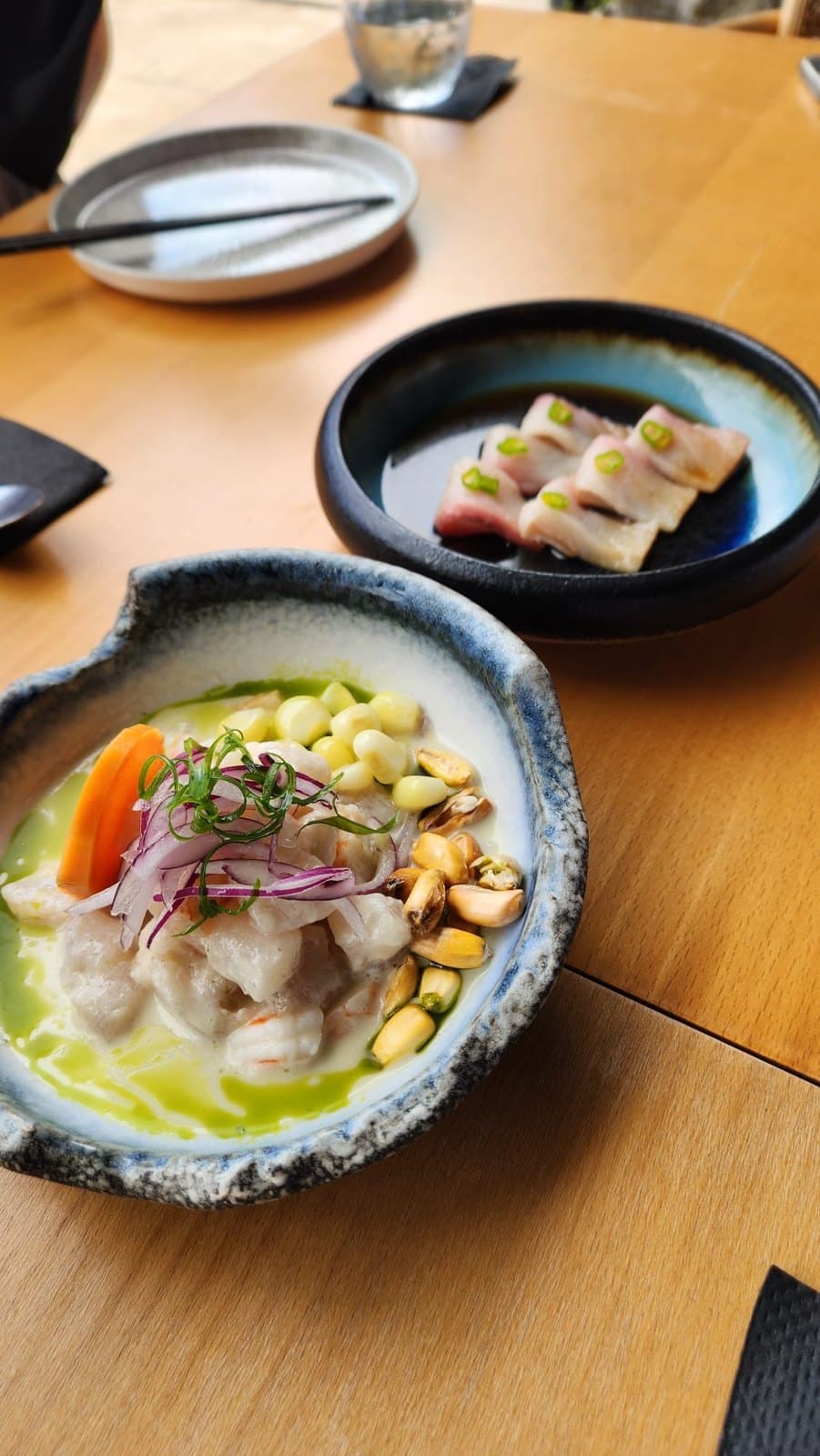 Tiradito in leche de tigre at Lima Nikkei, with corn and red onion in a pale bowl