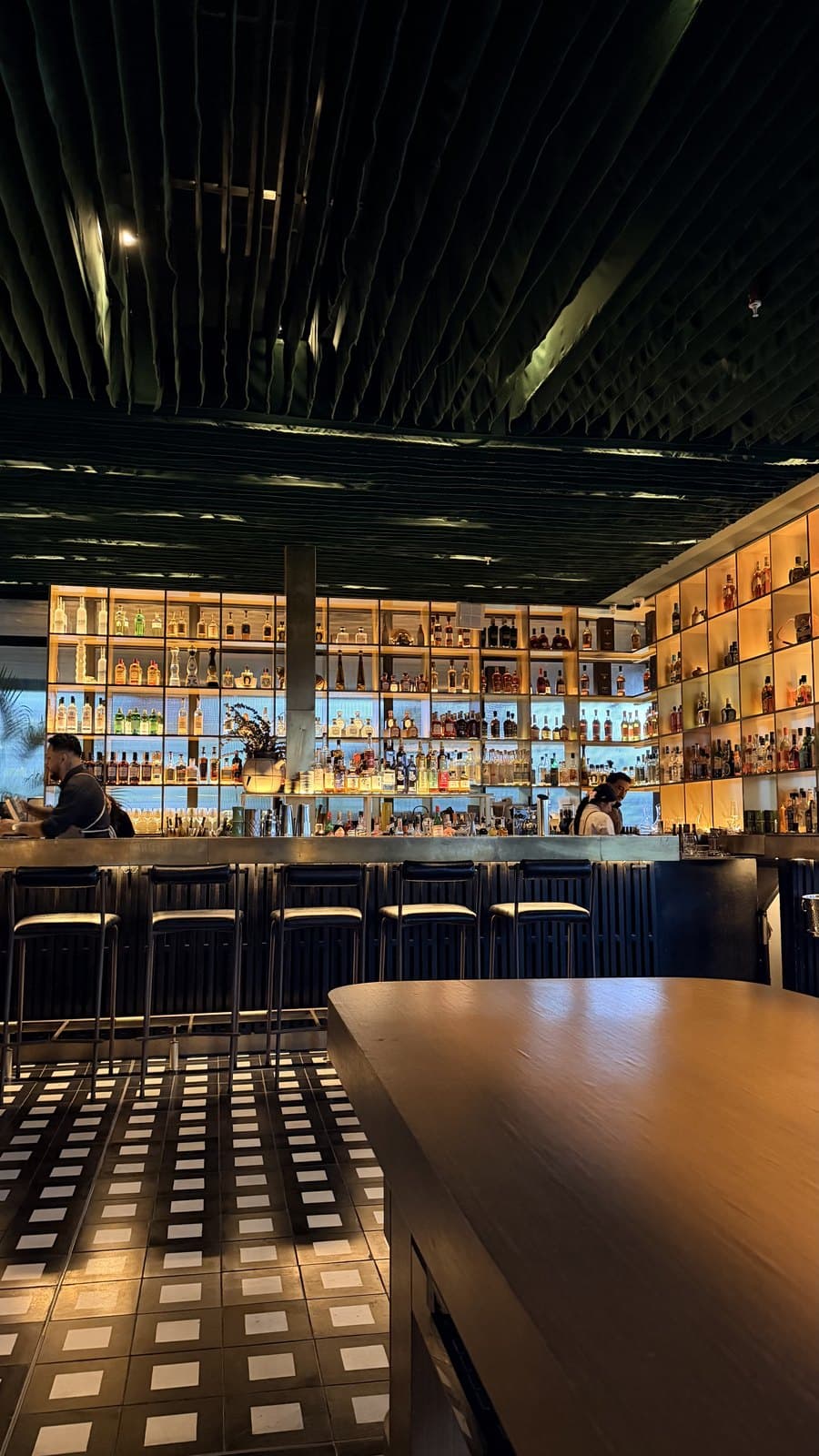 The backlit bottle wall, bar stools and black-and-white tile floor at Mai Mai, Costa del Este, Panama City