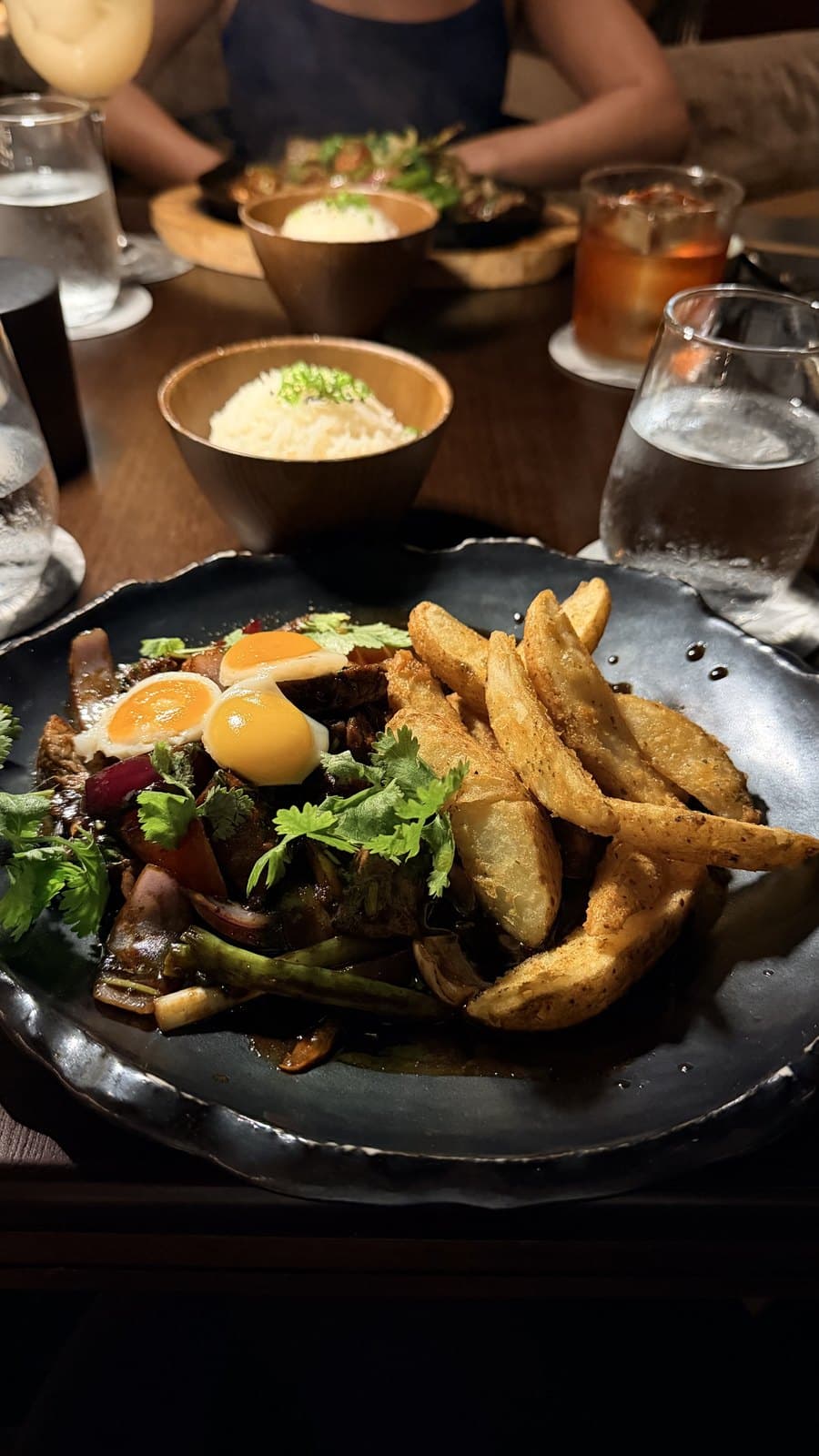 Lomo saltado at Mai Mai, beef and red onion under two fried quail eggs with thick-cut potatoes, a bowl of rice behind it