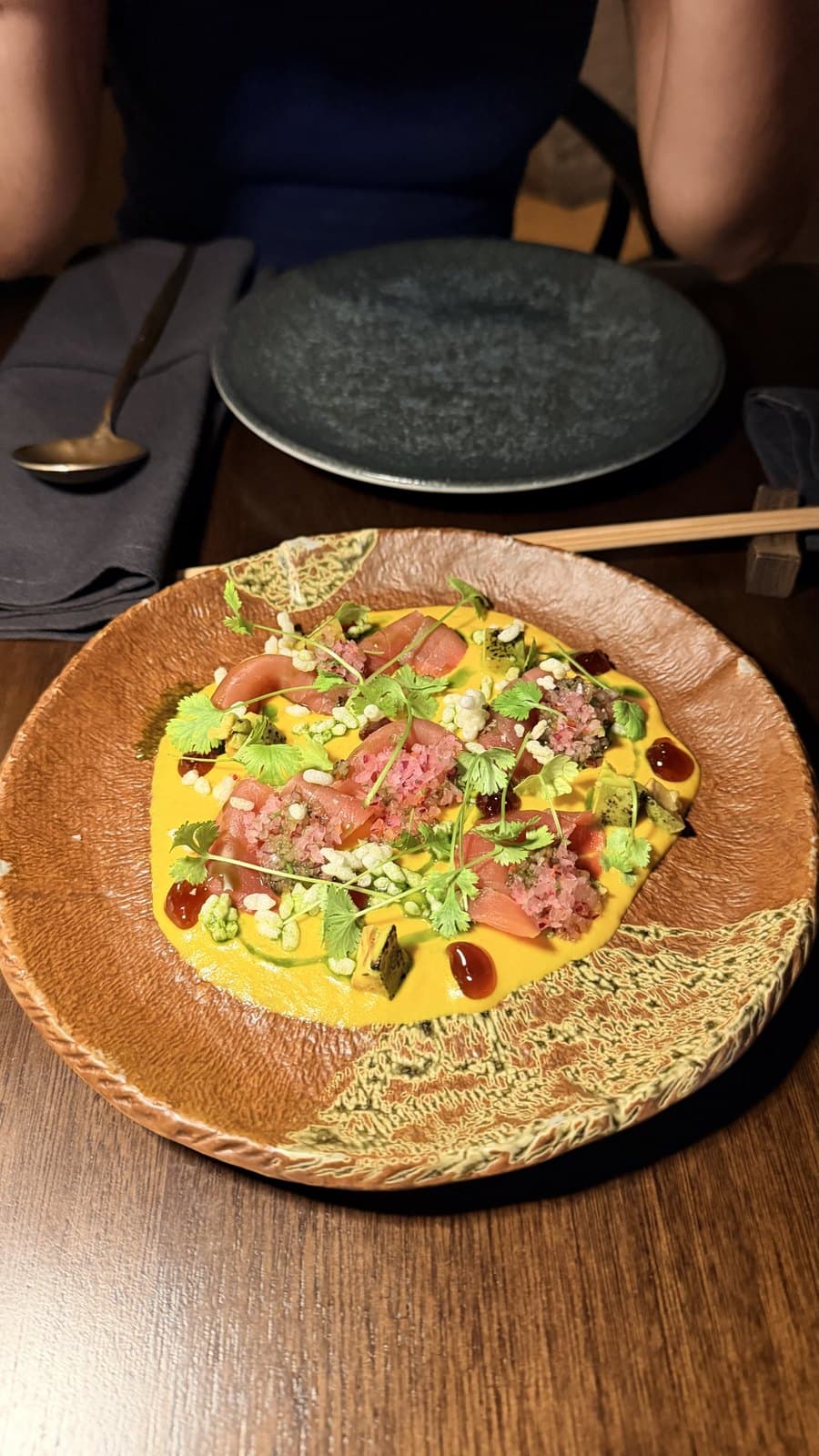 Toro tartar at Mai Mai, tuna over a bright yellow sauce with cilantro, avocado and puffed grains in a wide terracotta bowl