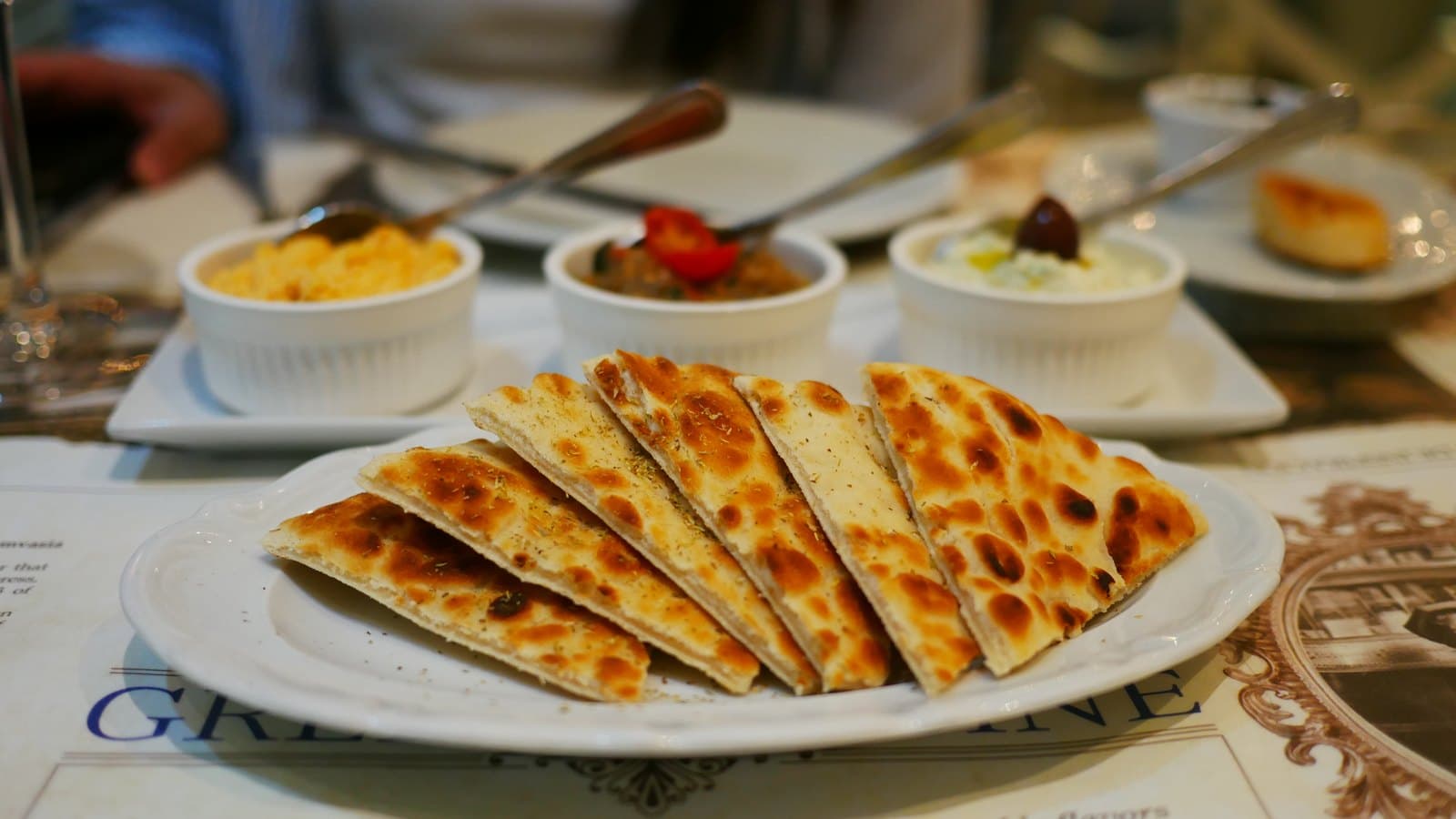 The Trilogy appetiser at Meze: three dips in small bowls with a plate of sliced pita