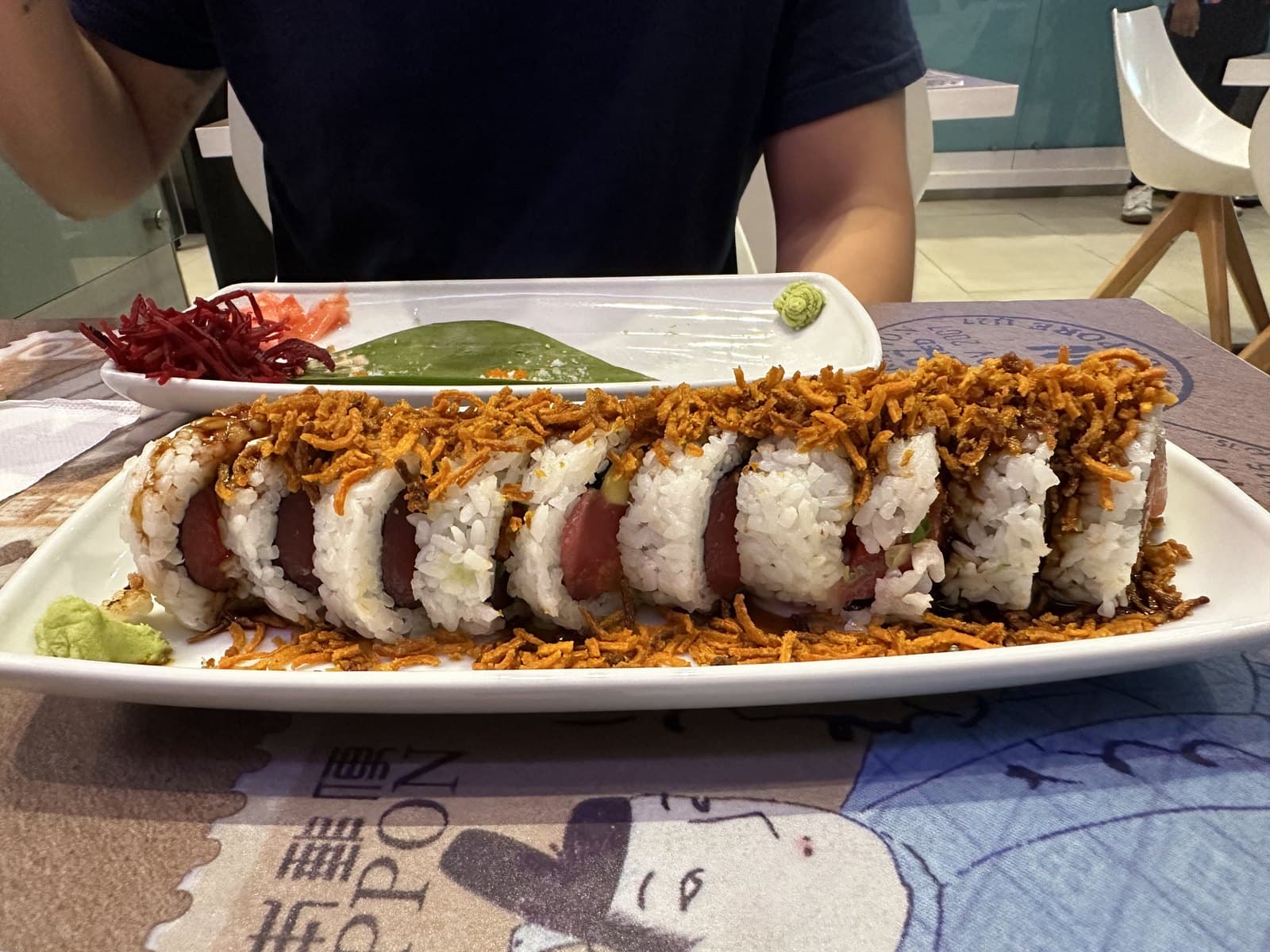 The Amor Disco roll at Nacion Sushi, a long sliced roll topped with crisp strands on a white plate