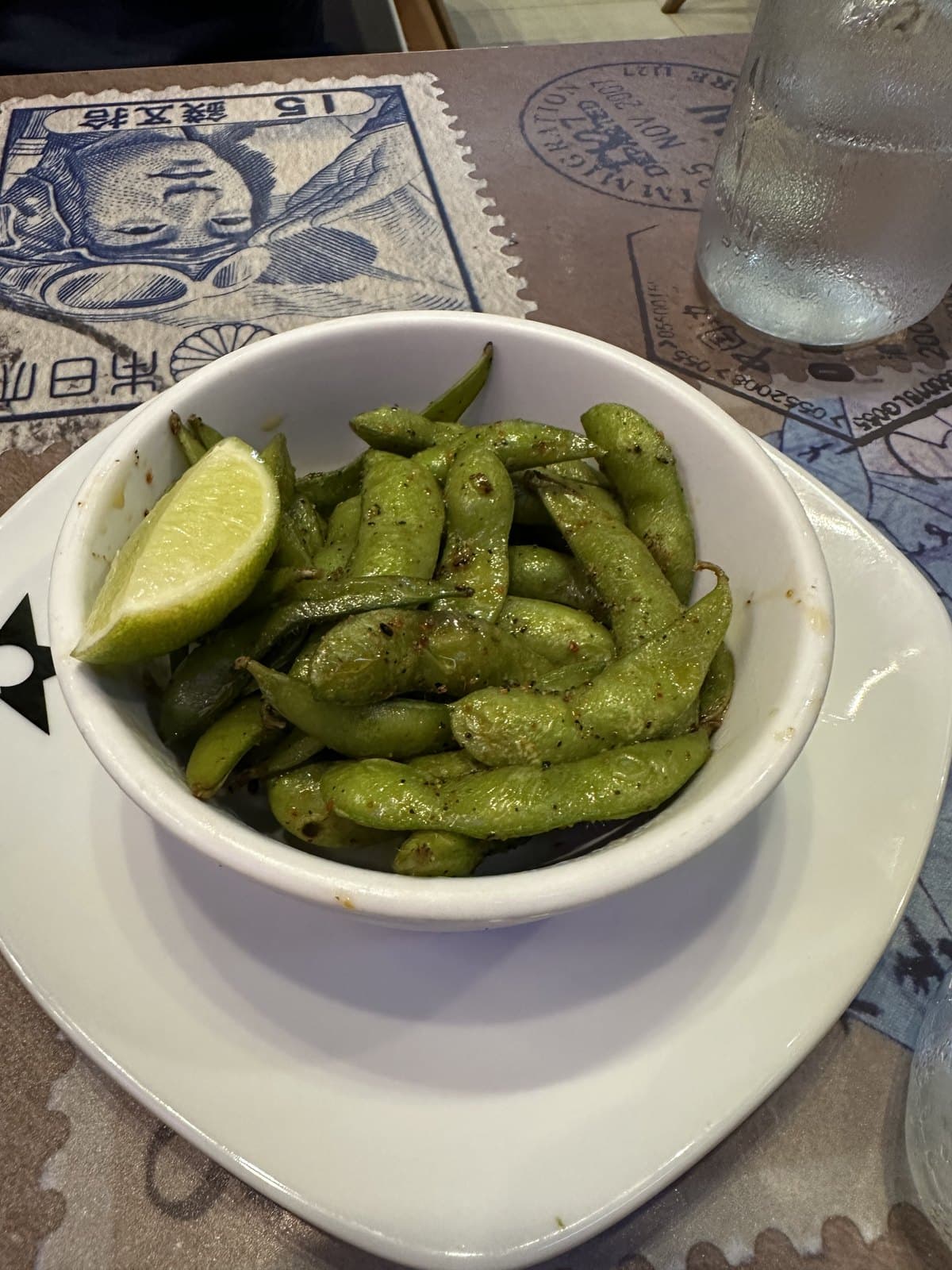 Thai edamame at Nacion Sushi, served in a white bowl with a wedge of lime