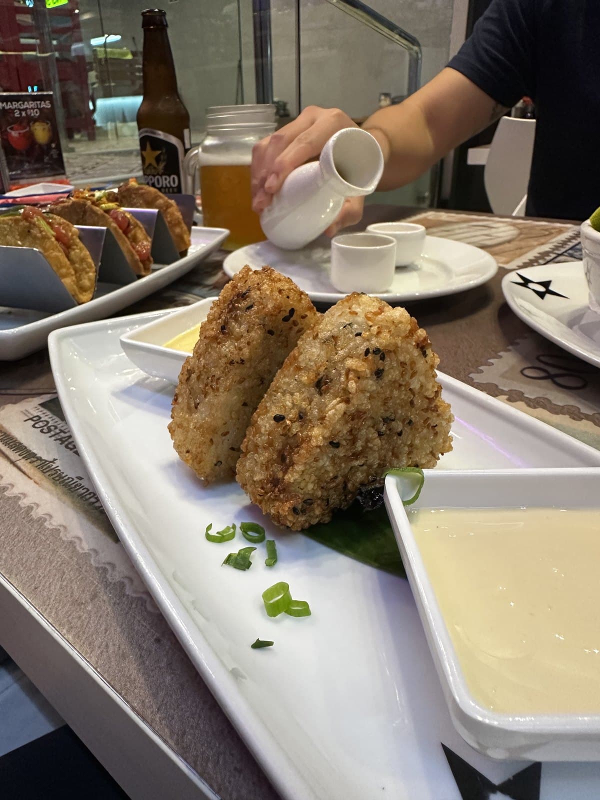 Tuna onigiri at Nacion Sushi, two sesame-crusted rice triangles with a dipping sauce