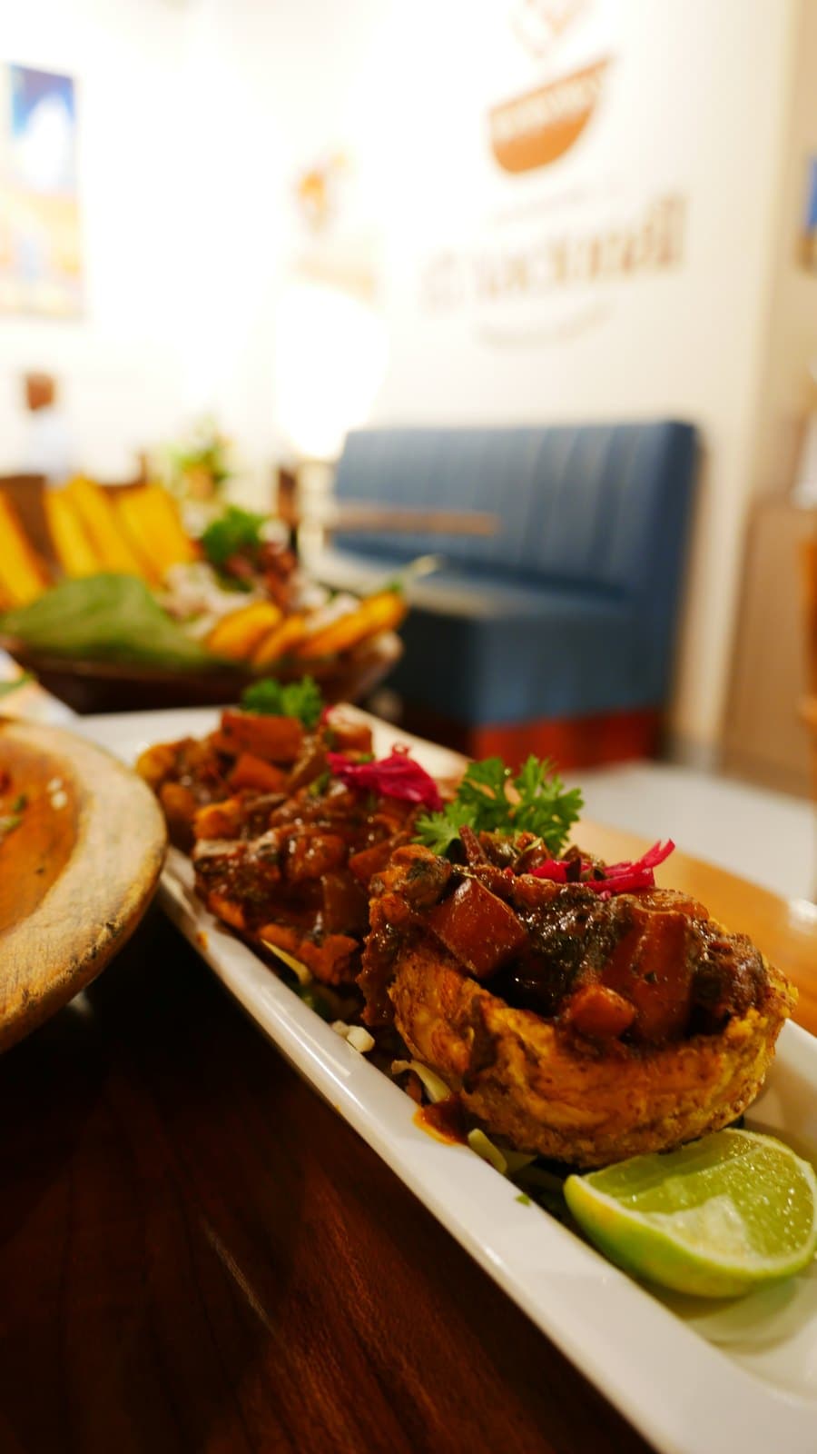 Patacones topped with seafood in a coconut sauce, served on a long white plate at El Nacional