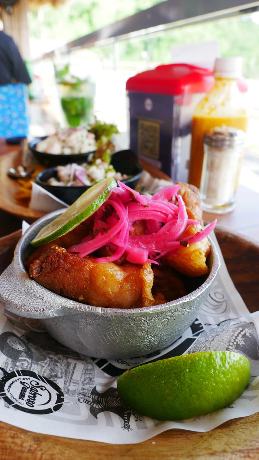Crispy pork belly at Sabroso topped with pickled red onion in a small metal pot