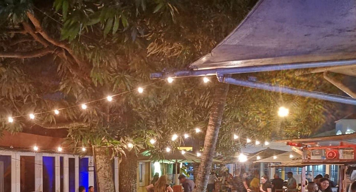 Open-air garden patio at night under a mango tree strung with festoon lights at Palo 'e Mango, Albrook, Panama City
