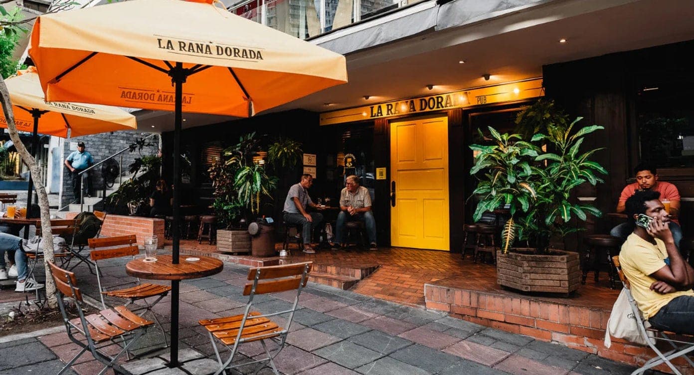 Terraza al aire libre con sombrillas naranjas y mesas en La Rana Dorada, Vía Argentina, Bella Vista, Ciudad de Panamá