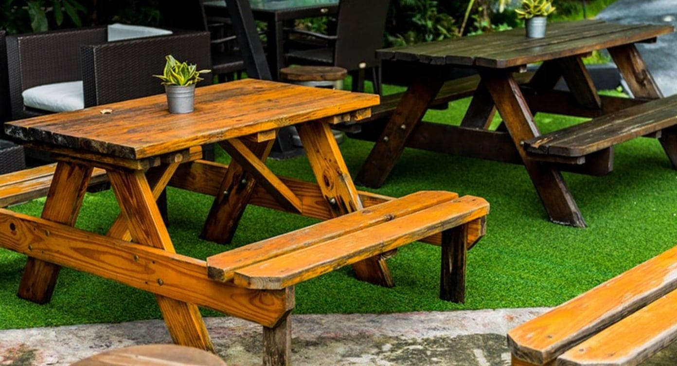 Open-air beer garden with wooden picnic tables and tropical greenery in El Cangrejo, Panama City