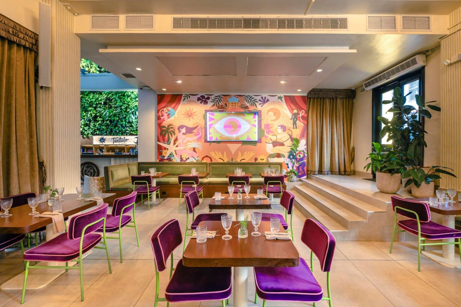 Interior dining room with purple velvet chairs and a living green wall at Alura, Casco Viejo, Panama City