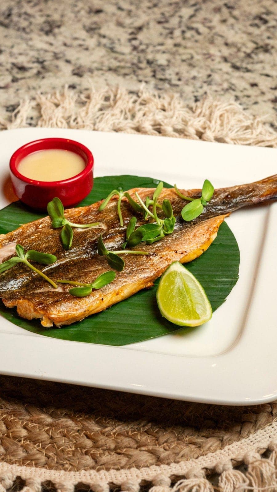Whole grilled fish plated on a banana leaf with lime at Aya la Vida, Casco Viejo, Panama City