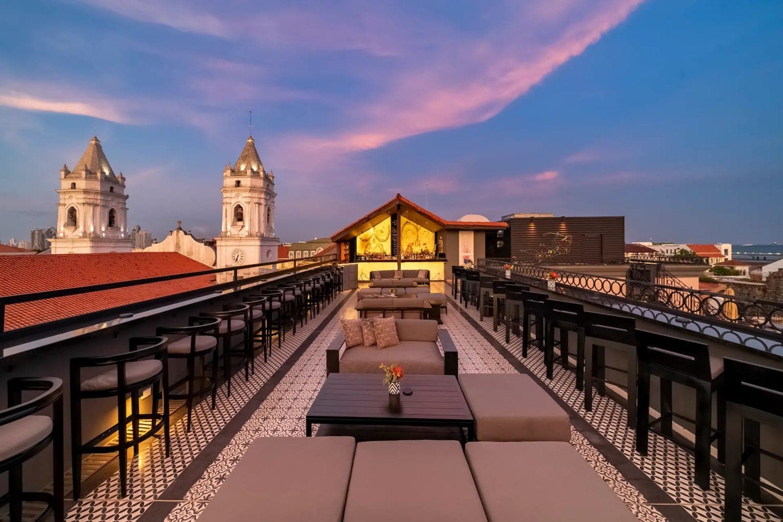 Terraza rooftop al atardecer con las torres de la catedral y el horizonte de la ciudad en Capella Rooftop, Casco Viejo