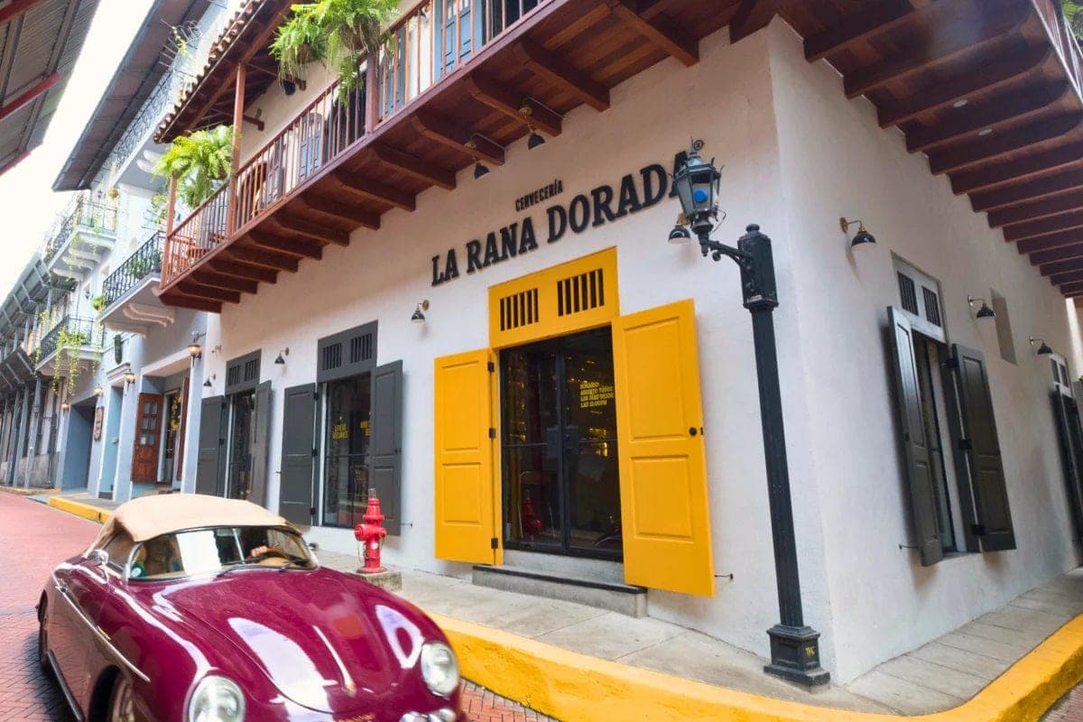 Colonial corner facade of the La Rana Dorada Casco Antiguo brewpub with yellow shutters on a cobblestone street, Panama City