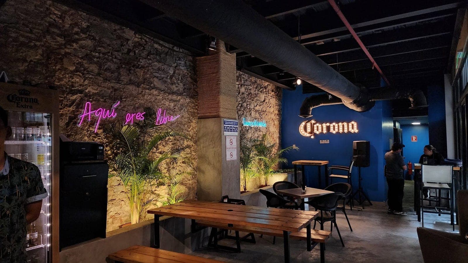 Interior with a stone wall, neon sign and communal tables at Marea Casco, Casco Viejo, Panama City