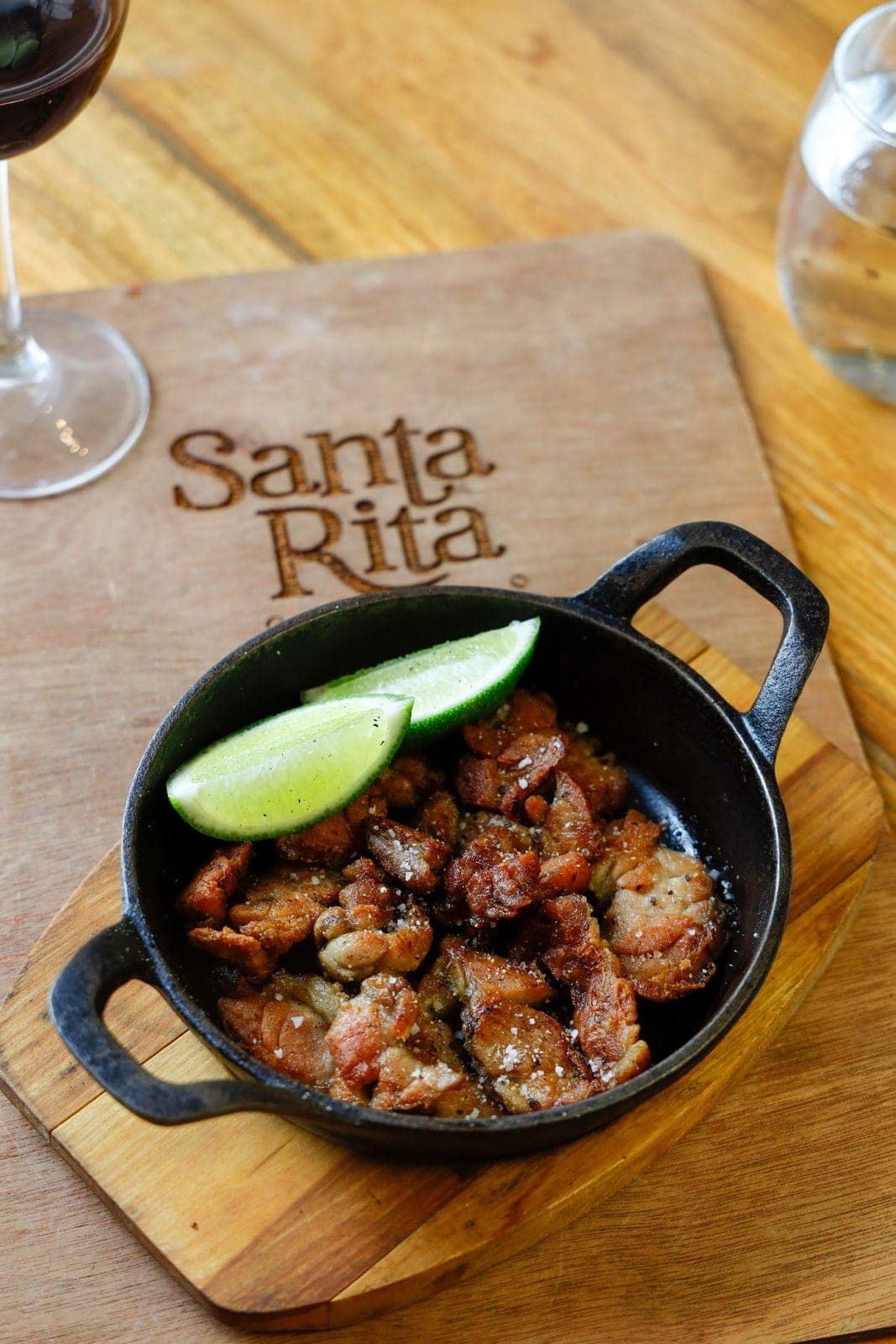 Fried pork dish in a cast-iron pan on a Santa Rita branded board, Casco Viejo, Panama City