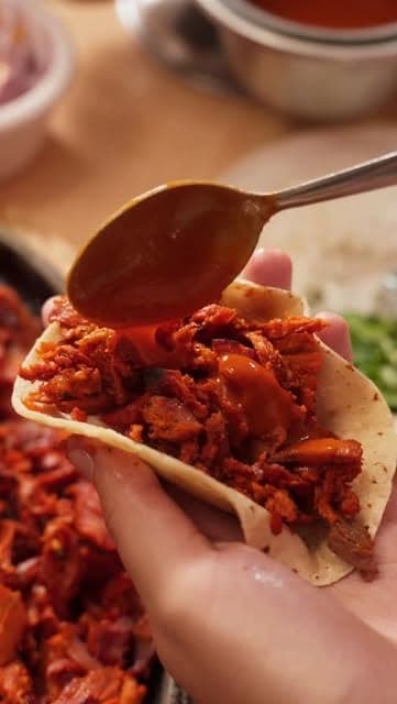 Al pastor taco with salsa being spooned over it at Tacos Taqueria Los Tarascos de Mexico, Costa del Este, Panama City