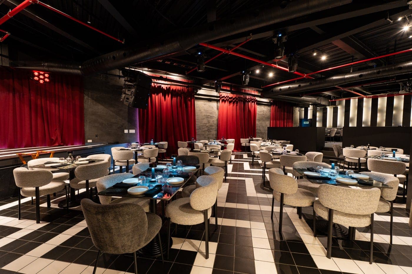 Interior dining and bar setting with checkerboard floor, set tables and red curtains at Terraplén Rooftop, Casco Viejo, Panama City